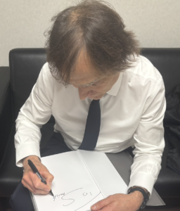 仙台市宮城野区のインプラント治療をリードするしらとり歯科医院へ、Urban先生が最新の骨造成書籍にサインをする様子